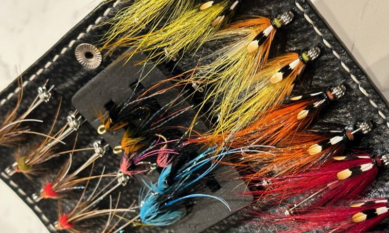 A selection of salmon tubes & flies with a handcrafted wallet